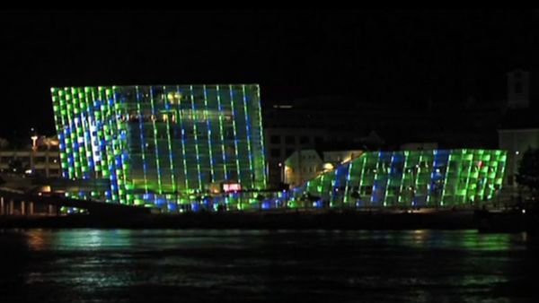 Ars Electronica Center, its facade lights up in green and blue colors.